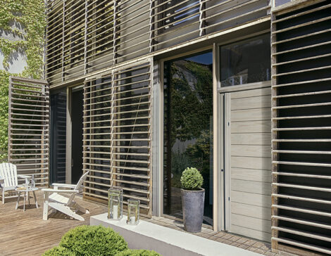 porte d'entrée en bois massif sur une façade de maison contemporaine avec des lames de bois et des fenêtres
