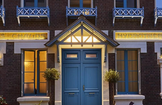 Porte Bel'M pleine en Aluminium modèle Odyssée style classique avec imposte vitrée sur une maison en briques de nuit avec éclairages d'ambiance