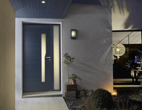 extérieure d'une maison avec un luminaire extérieur en applique et une porte d'entrée avec un semi fixe vitré