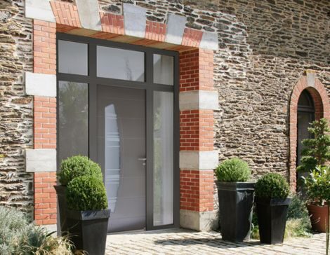 maison ancienne en pierre avec une porte d'entrée contemporaine avec 2 fixes vitrés et une imposte