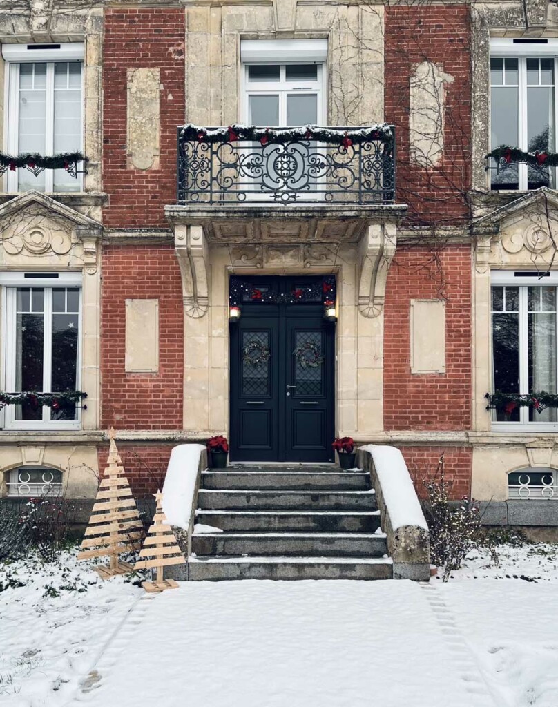 porte d'entrée classique avec décoration de noel sur une maison de maître, entourée de neige