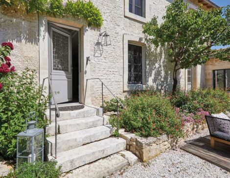 Une porte d'entrée sur une maison ancienne en pierre, avec de la verdure environnante