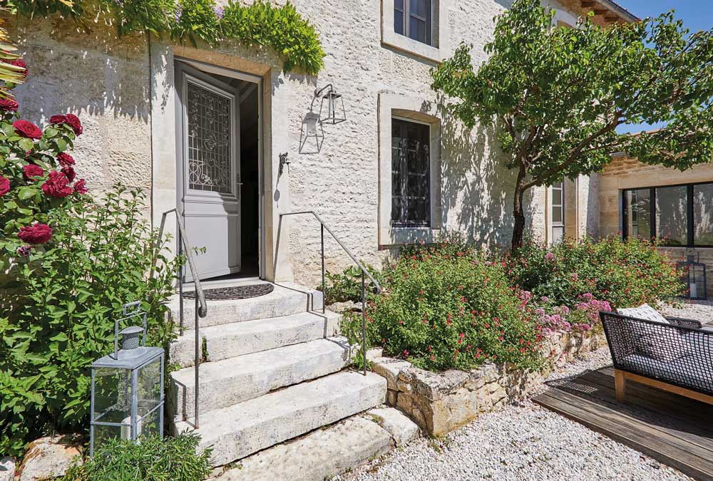Une porte d'entrée sur une maison ancienne en pierre, avec de la verdure environnante