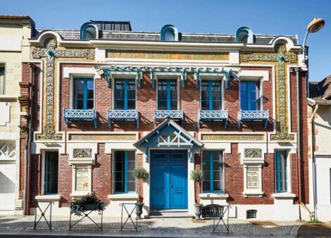 façade en brique avec une porte d'entrée et des volets bleus