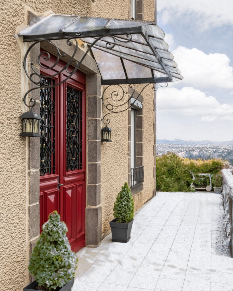 porte entrée rouge avec une marquise en verre, agrémentée de neige