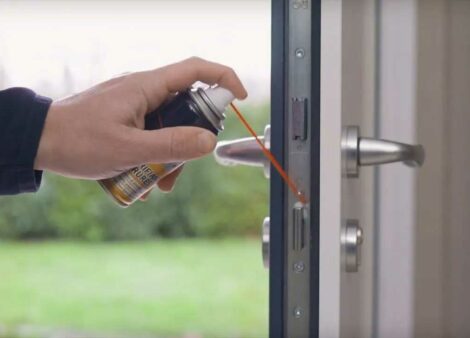 une personne lubrifie une serrure de porte d'entrée de maison