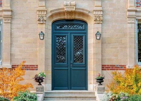 une porte d'entrée traditionnelle en bois, sur une façade de maison de maitre