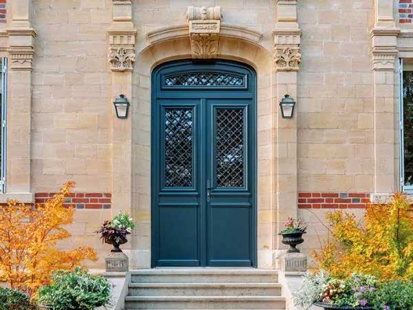 une porte d'entrée traditionnelle en bois, sur une façade de maison de maitre