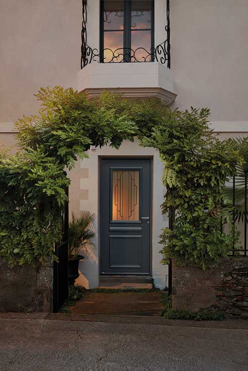 une maison de ville avec une porte d'entrée avec une vitrage. Ambiance de nuit. 