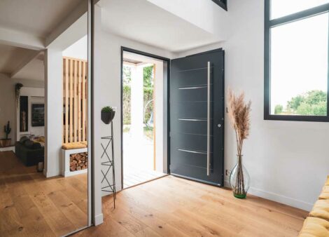 intérieur de maison moderne avec une porte d'entrée pleine avec une barre de tirage. La porte est ouverte.