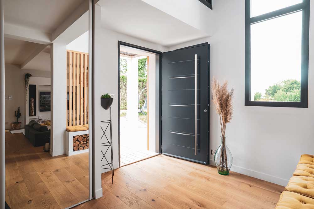 intérieur de maison moderne avec une porte d'entrée pleine avec une barre de tirage. La porte est ouverte.