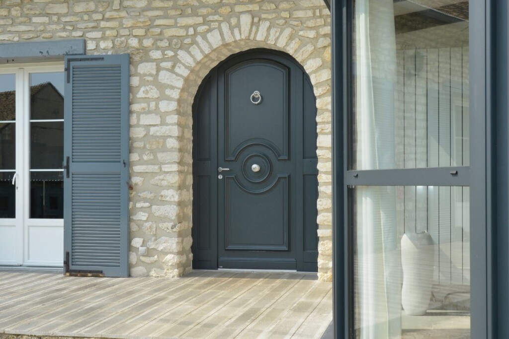 porte d'entrée en bois cintrée sur une maison en pierre