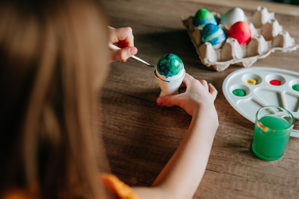 une petite fille qui peint des œufs de pâques