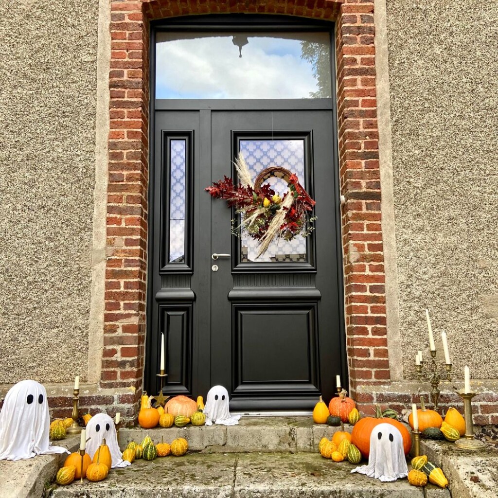 porte d'entrée bel'm décorée pour halloween avec une couronne automnale, des fantômes DIY et des courges et chandeliers 