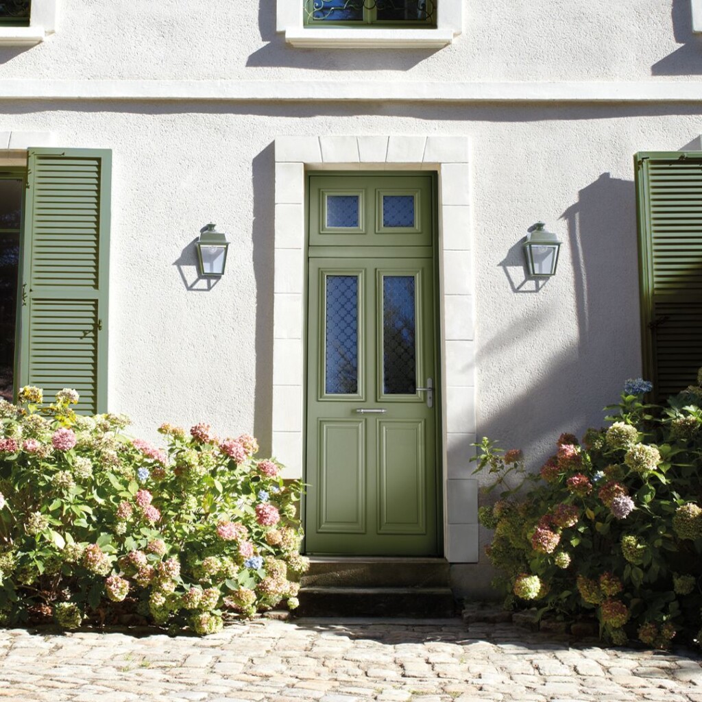 porte d'entrée de couleur verte sur une maison entourée de verdure