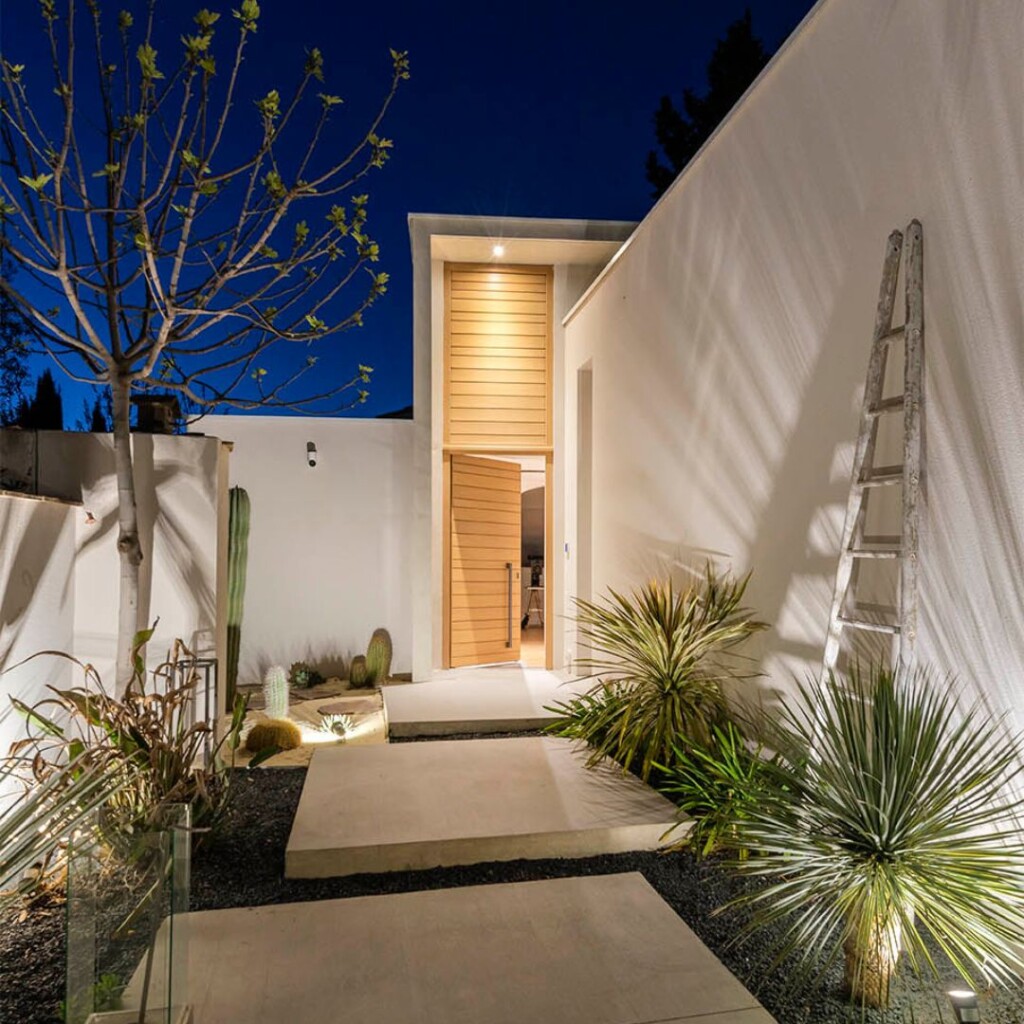 entrée de maison avec un chemin entouré de leds au sol, avec une porte d'entrée en bois moderne