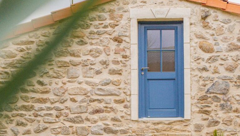 maison en pierre avec une porte d'entrée en bois vitrée avec des petits bois collés