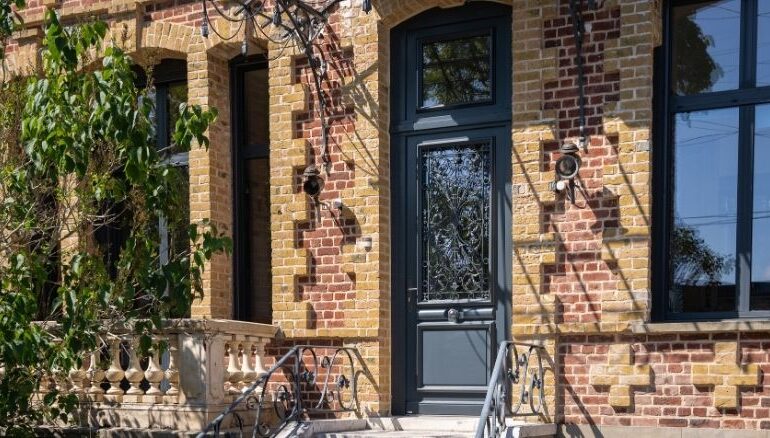porte d'entrée en bois sur mesure au style traditionnel sur une maison en brique