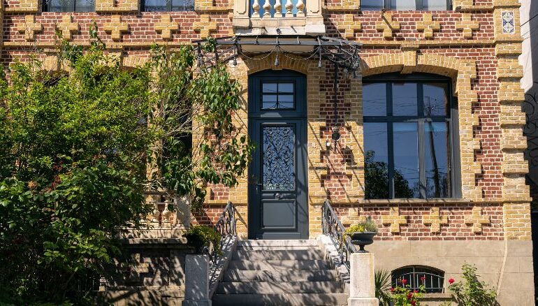maison en brique avec une porte d'entrée en bois sur mesure