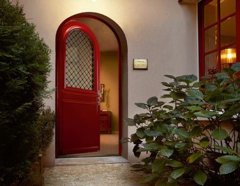 porte d'entrée cintrée en bois rouge basque avec un vitrage et une grille traditionnelle